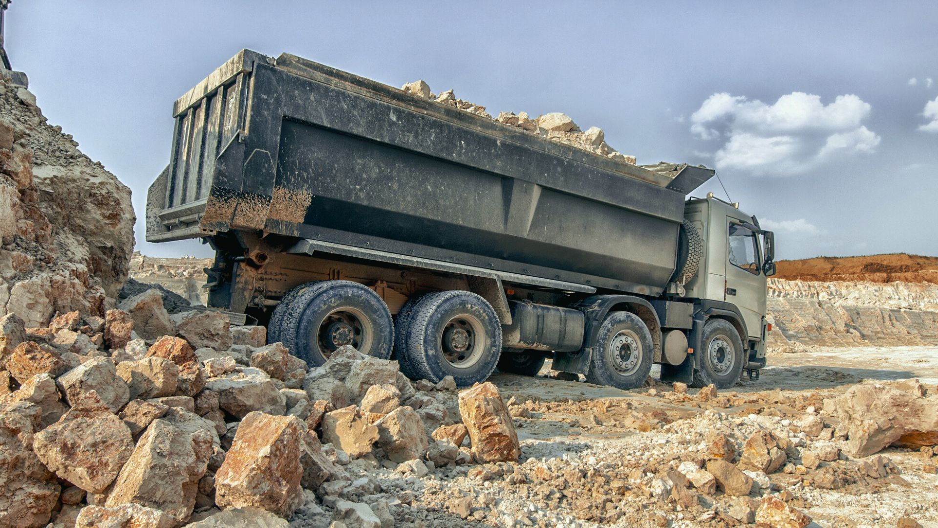 long aggregate hauling truck backing up to a gravel pile