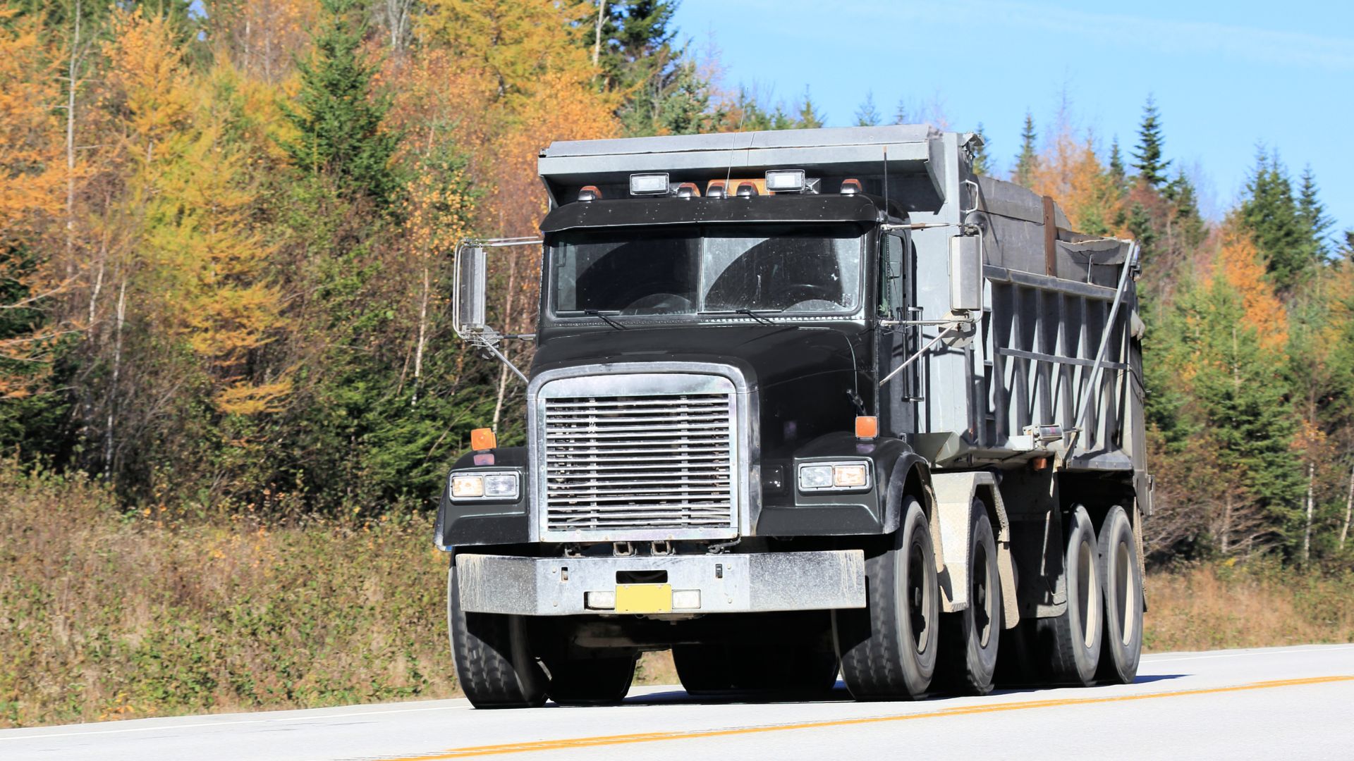 black kenworth quad axle dump truck driving odwn the road